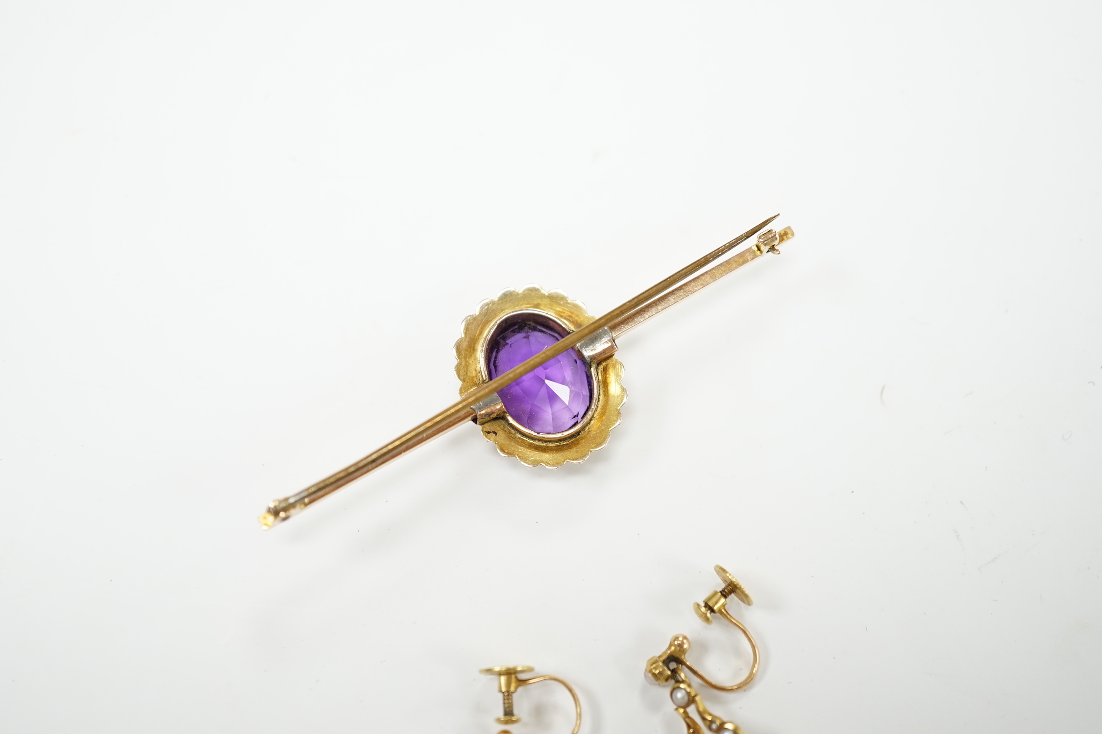 A yellow metal, amethyst and seed pearl cluster set bar brooch, 65mm and a pair of similar drop ear clips, gross weight 10 grams.